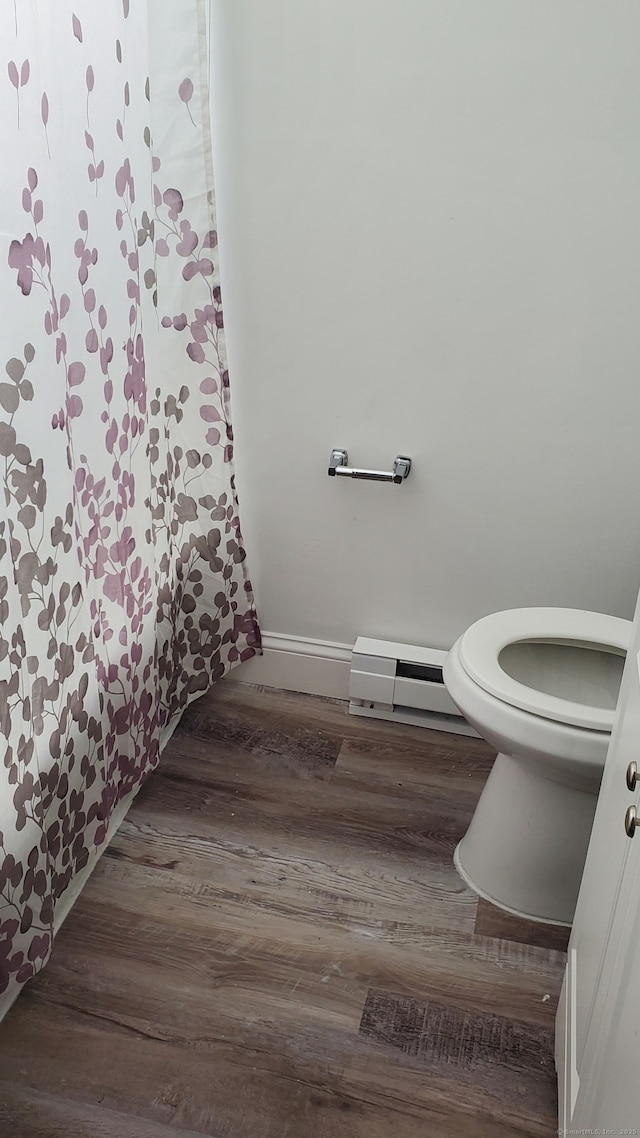 bathroom with toilet, baseboards, baseboard heating, and wood finished floors