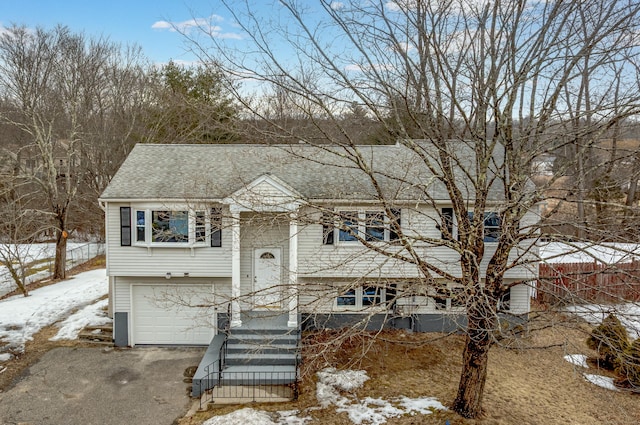 bi-level home featuring a garage, driveway, and a shingled roof