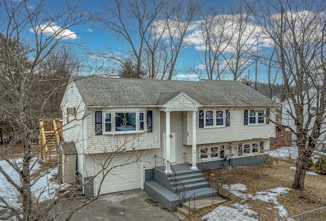 split foyer home featuring roof with shingles and an attached garage