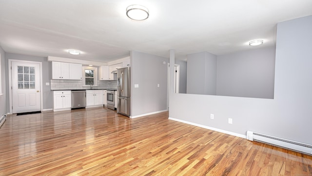 unfurnished living room featuring light wood-type flooring, a baseboard radiator, a sink, and baseboards