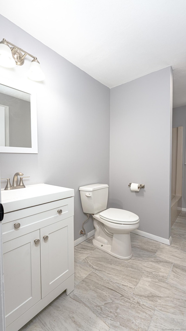 bathroom with toilet, baseboards, and vanity