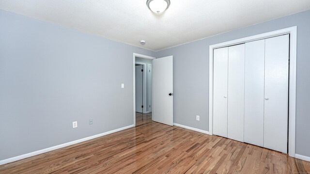 unfurnished bedroom featuring a closet, wood finished floors, and baseboards