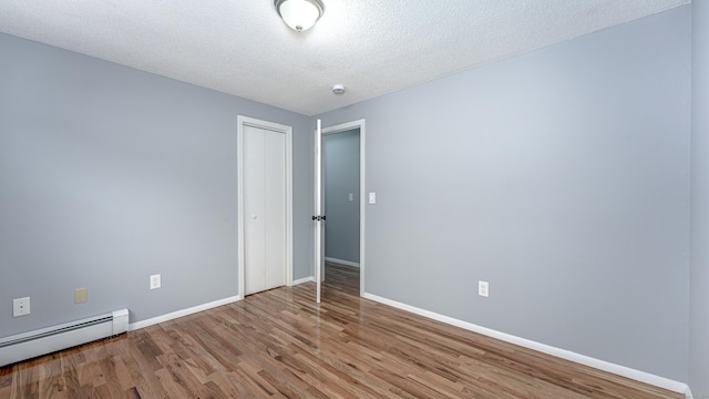 spare room with a textured ceiling, a baseboard radiator, wood finished floors, and baseboards