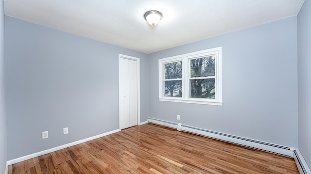 spare room featuring baseboards, baseboard heating, and wood finished floors