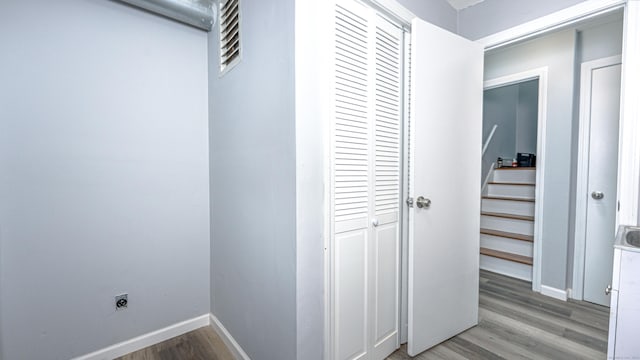 hallway featuring baseboards, stairway, visible vents, and light wood-style floors