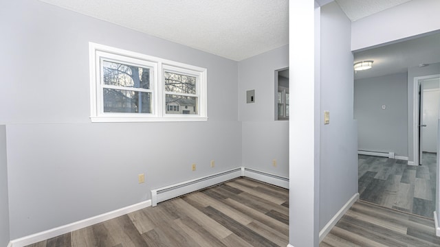 spare room with a baseboard heating unit, a textured ceiling, a baseboard radiator, and wood finished floors