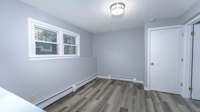 spare room with baseboards, a textured ceiling, baseboard heating, and wood finished floors