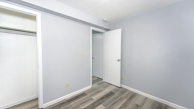 unfurnished bedroom with a closet, baseboards, and wood finished floors