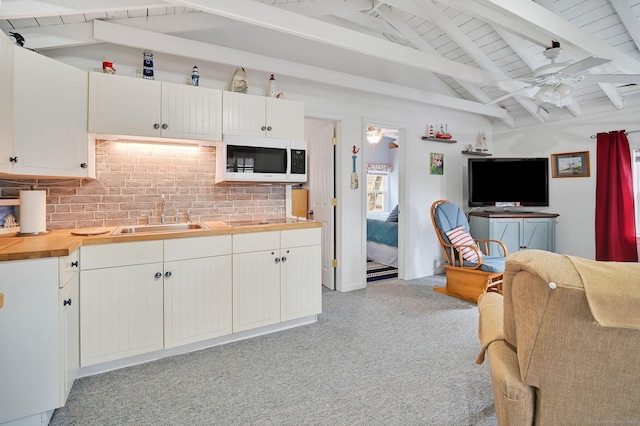 kitchen with ceiling fan, white microwave, butcher block countertops, a sink, and open floor plan