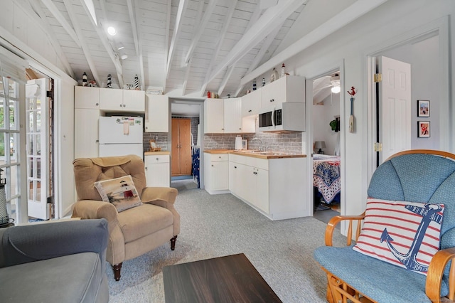 living area with lofted ceiling with beams and light colored carpet