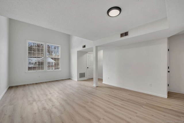 spare room with light wood finished floors, visible vents, and baseboards