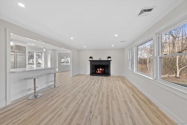 unfurnished living room with a wealth of natural light, visible vents, a warm lit fireplace, and baseboards