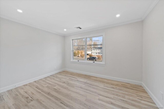 empty room featuring ornamental molding, wood finished floors, visible vents, and baseboards