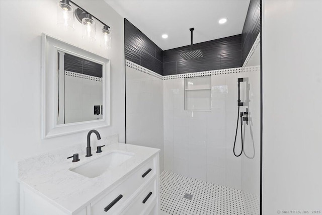 bathroom with recessed lighting, tiled shower, and vanity