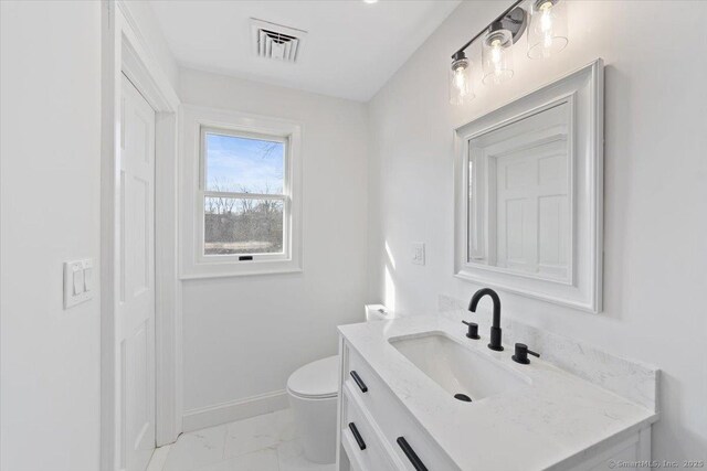 bathroom featuring toilet, vanity, visible vents, baseboards, and marble finish floor