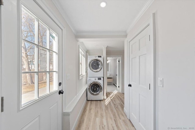 washroom featuring stacked washer and dryer, light wood-style floors, a wealth of natural light, and ornamental molding