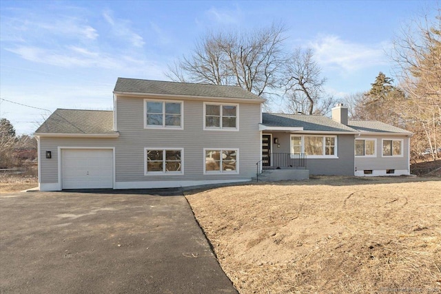 tri-level home with a garage, aphalt driveway, and a chimney