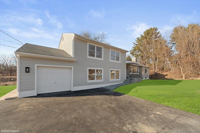 view of front of home with aphalt driveway, an attached garage, and a front yard