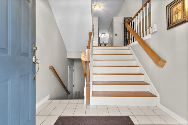 staircase with baseboards and tile patterned floors