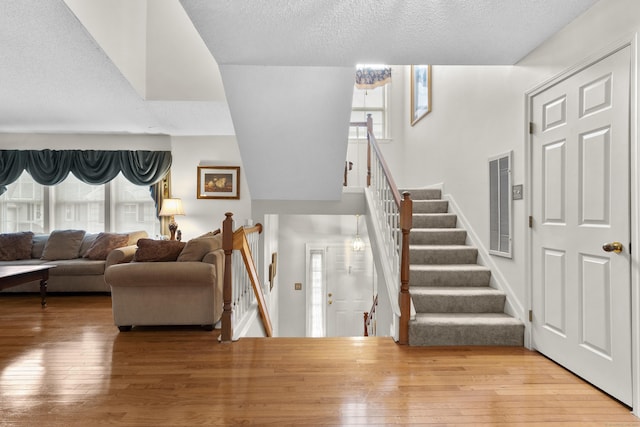 foyer with wood-type flooring, stairs, visible vents, and a textured ceiling