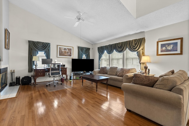 living area featuring a textured ceiling, ceiling fan, high vaulted ceiling, and light wood-style floors