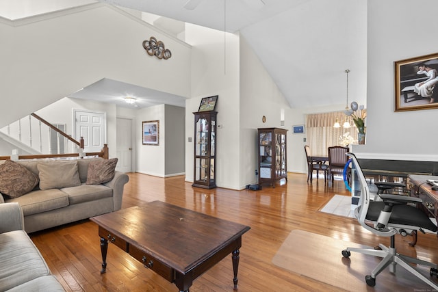 living area featuring light wood-style floors, baseboards, stairway, and high vaulted ceiling