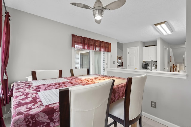 dining space featuring baseboards, a ceiling fan, and a textured ceiling