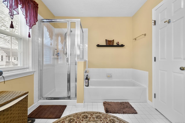 bathroom with a stall shower, a garden tub, a textured ceiling, and tile patterned floors