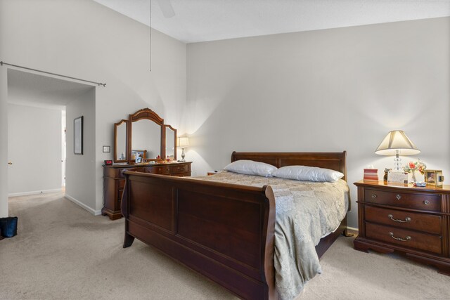 bedroom with ceiling fan, baseboards, and light colored carpet