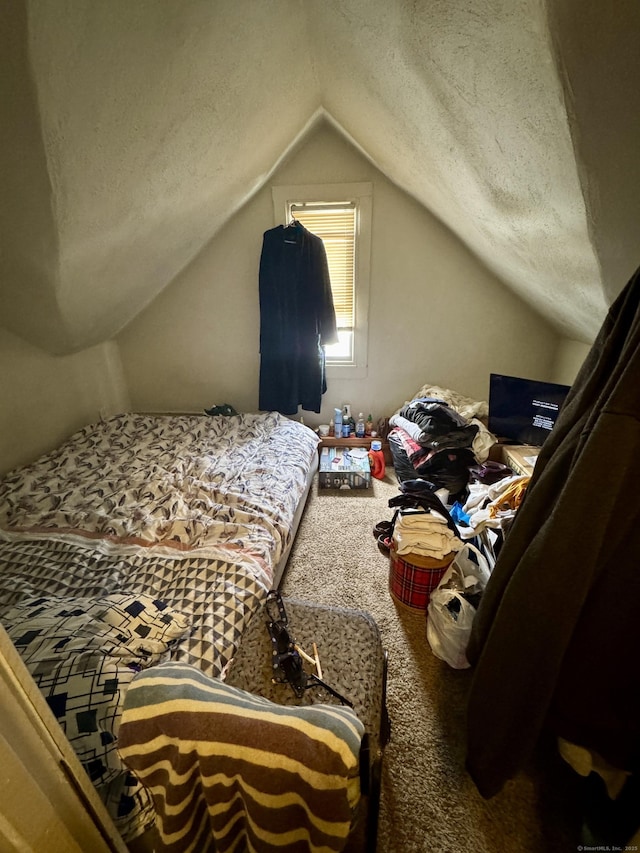 bedroom featuring carpet, vaulted ceiling, and a textured ceiling