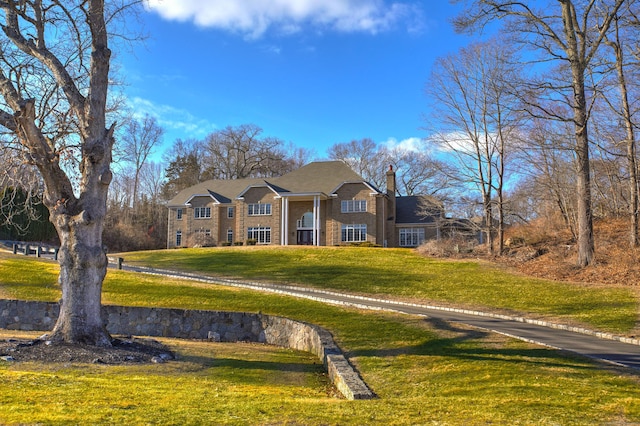 view of front facade featuring a chimney and a front lawn