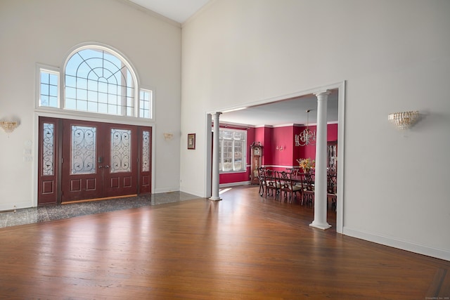 entrance foyer featuring crown molding, decorative columns, a high ceiling, and wood finished floors