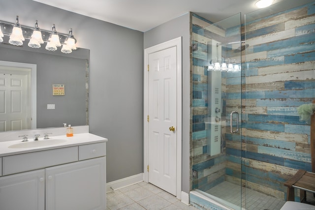 bathroom featuring tile patterned flooring, baseboards, a shower stall, and vanity