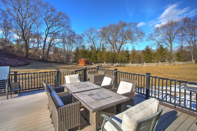 wooden terrace with an outbuilding, a shed, outdoor dining area, and a lawn