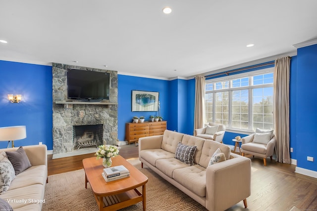 living area featuring a stone fireplace, recessed lighting, wood finished floors, and baseboards