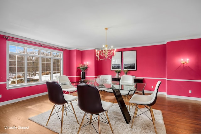 dining area featuring a chandelier, crown molding, baseboards, and wood finished floors