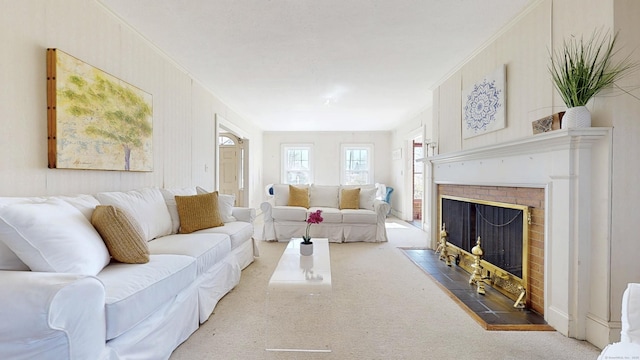 carpeted living room with a tiled fireplace and crown molding