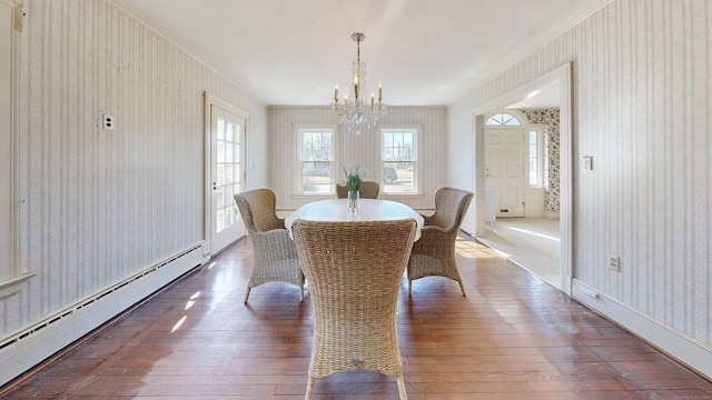 dining room with wallpapered walls, hardwood / wood-style floors, ornamental molding, an inviting chandelier, and a baseboard radiator