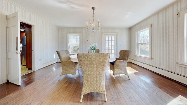 dining area with plenty of natural light, wallpapered walls, a baseboard heating unit, and wood-type flooring