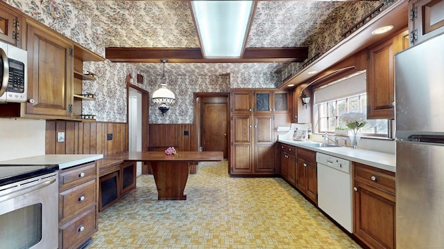 kitchen with wallpapered walls, a wainscoted wall, brown cabinets, stainless steel appliances, and open shelves