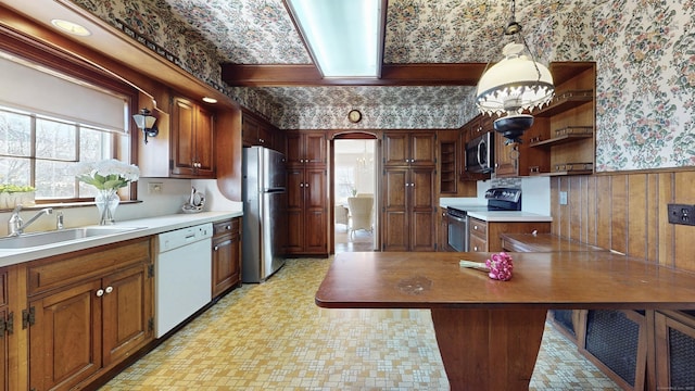 kitchen with arched walkways, a wainscoted wall, wallpapered walls, and stainless steel appliances