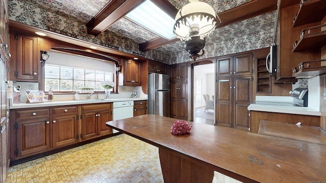 kitchen featuring open shelves, a peninsula, brown cabinetry, stainless steel appliances, and a sink