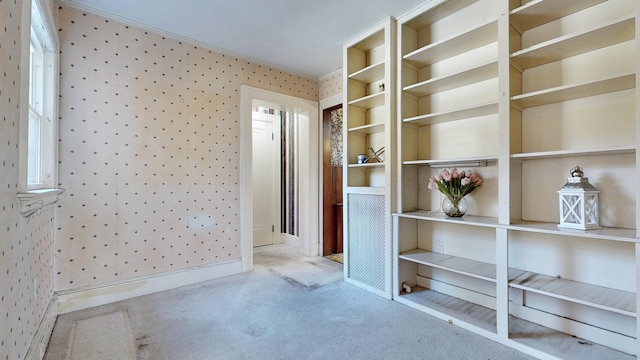 interior space with carpet flooring, wallpapered walls, crown molding, and baseboards