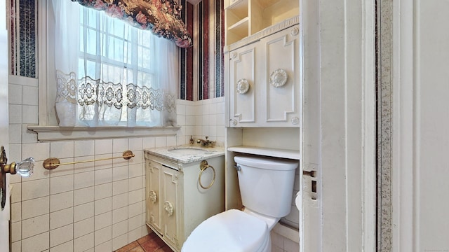 bathroom with toilet, tile walls, and vanity