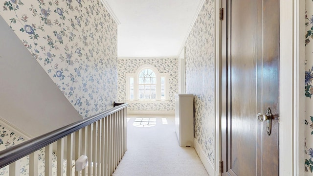 corridor featuring wallpapered walls, crown molding, and light colored carpet