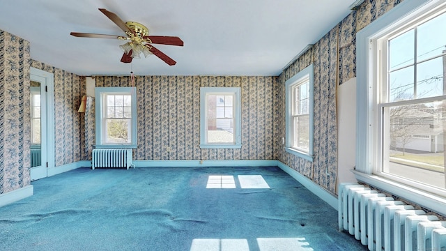 carpeted spare room featuring wallpapered walls, radiator heating unit, a ceiling fan, and baseboards