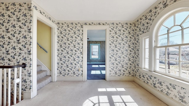 interior space with stairway, wallpapered walls, crown molding, and baseboards