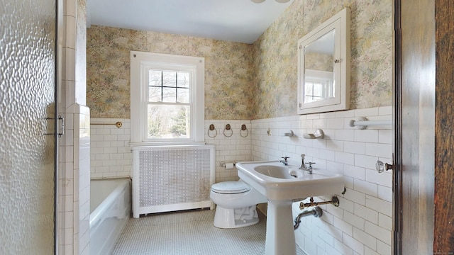 bathroom with a wainscoted wall, toilet, wallpapered walls, radiator, and tile patterned flooring