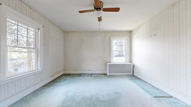 carpeted spare room featuring baseboards, a ceiling fan, radiator heating unit, and wallpapered walls