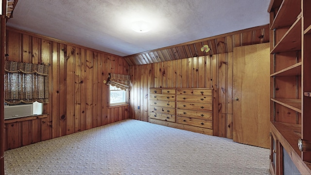 spare room featuring lofted ceiling, cooling unit, wood walls, and carpet floors